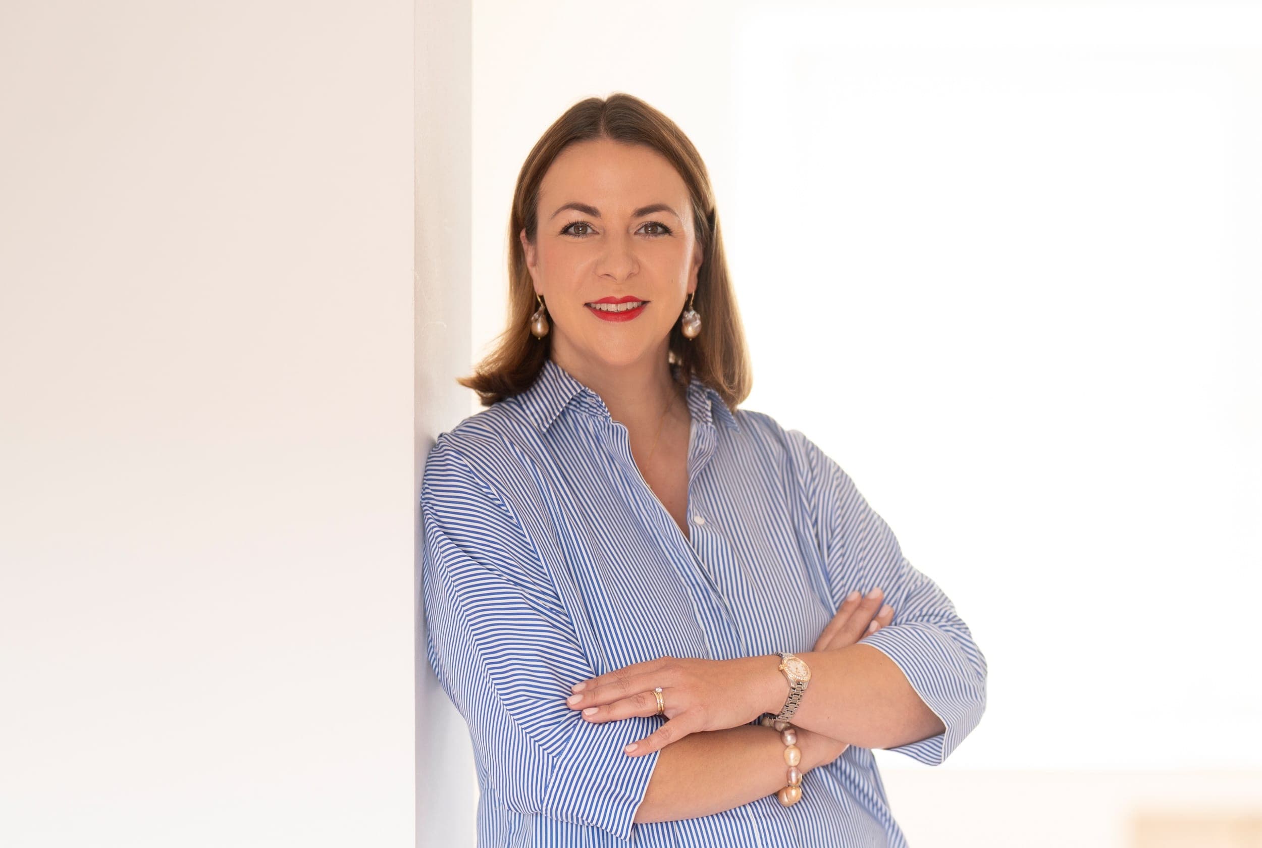 Victoria Beckers von Energie durch Entwicklung steht mit verschränkten Armen an einer hellen Wand und lächelt selbstbewusst in die Kamera – Porträtfoto mit positiver Ausstrahlung. Victoria Beckers von Energie durch Entwicklung steht mit verschränkten Armen an einer hellen Wand und lächelt selbstbewusst in die Kamera – Porträtfoto mit positiver Ausstrahlung.